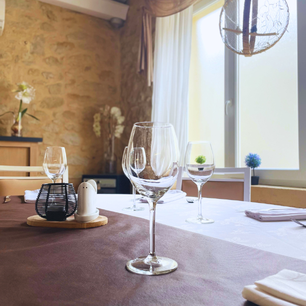 Verre de vin en premier plan au restaurant L’Absolu à Auros, reflet de l’ambiance raffinée et conviviale d’un repas gastronomique en Gironde