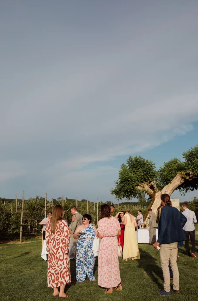 Invités réunis dans la cour en pierres apparentes du Château de Cantecort avec le service traiteur L’Absolu en arrière-plan